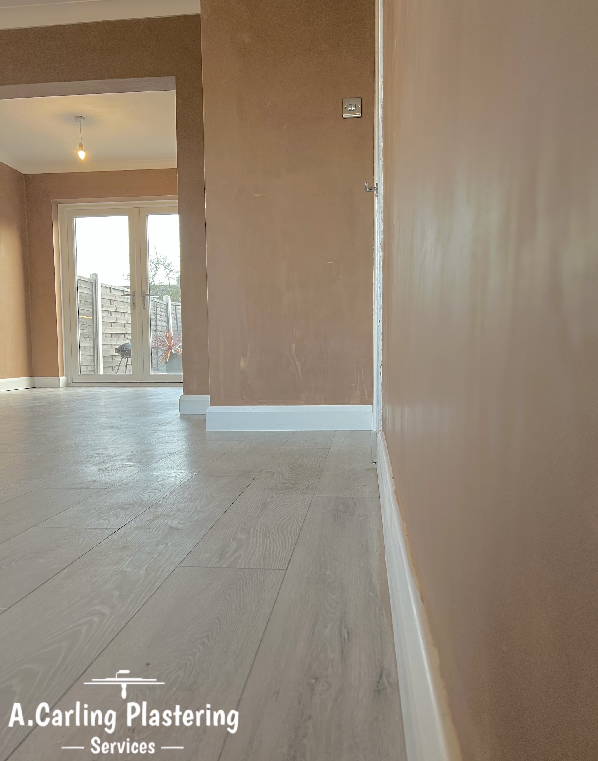 A hallway and through room freshly plastered, with new flooring down