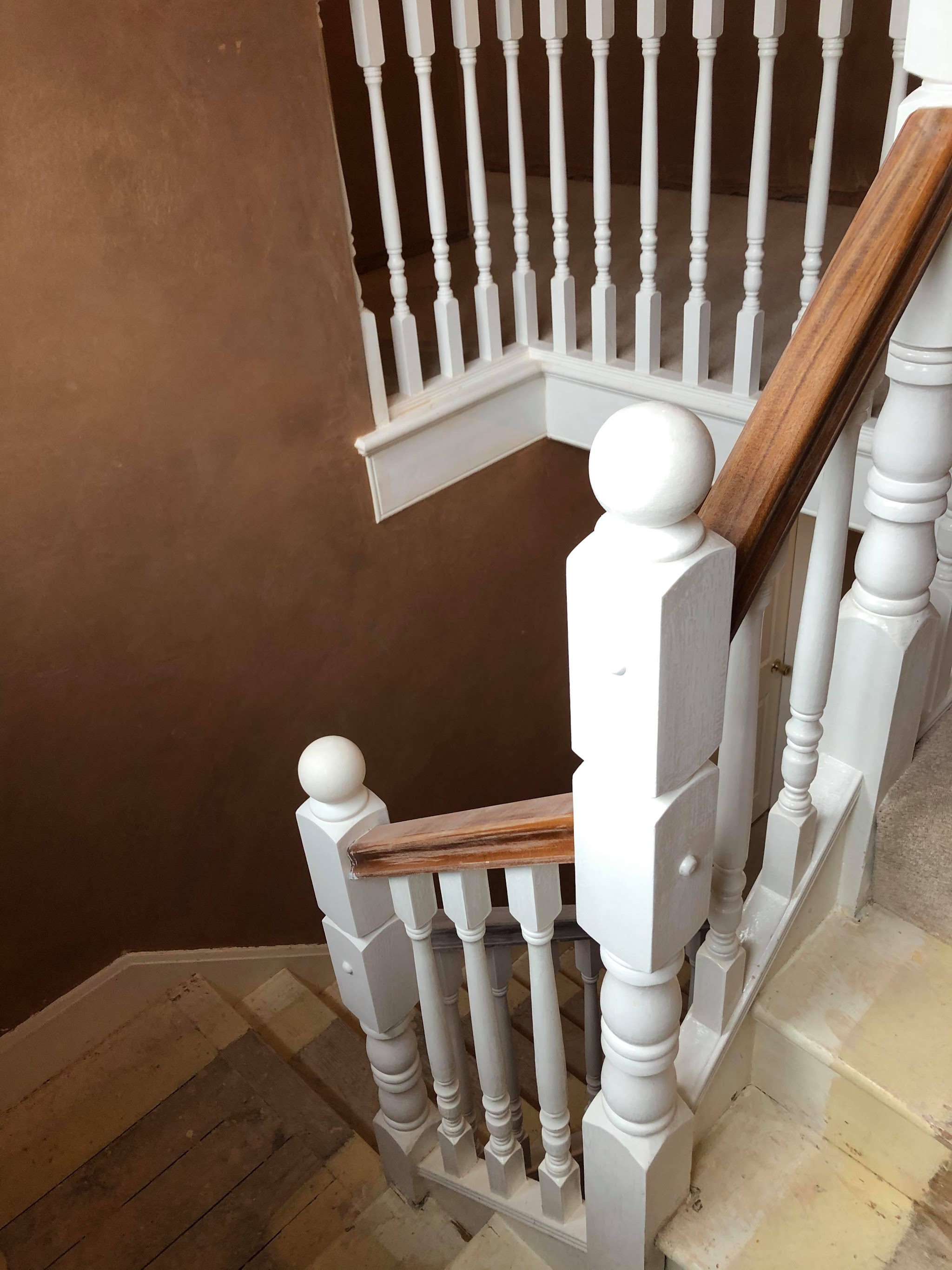 A staircase with white spindles beside newly plastered walls
