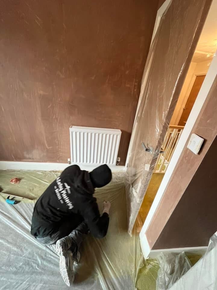 A plasterer at work with protective sheeting laid over the floor