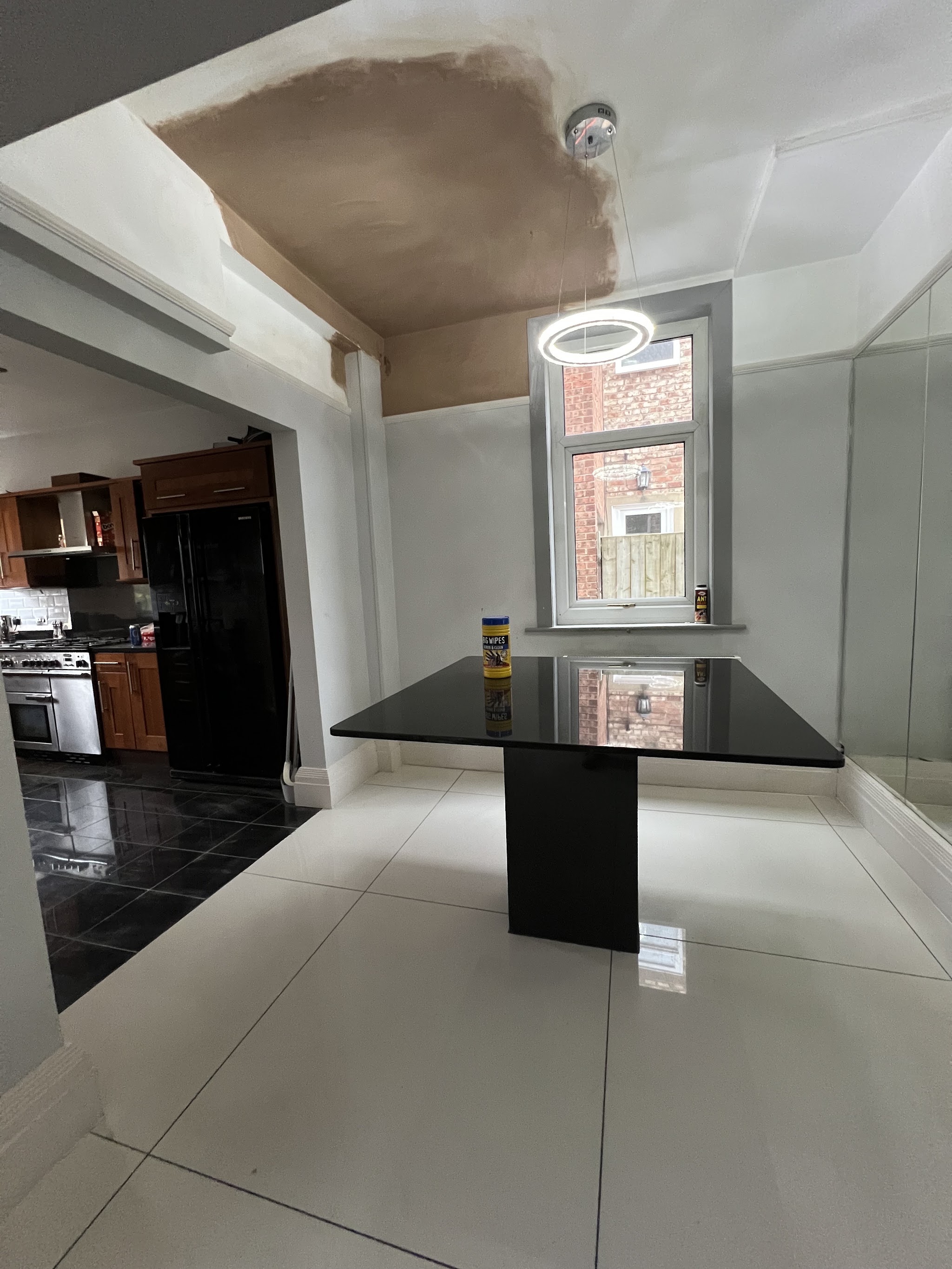 A kitchen diner with a newly plastered ceiling and a ring light